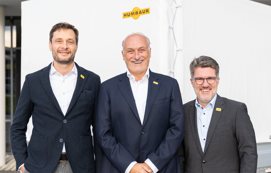 Drei Männer stehen vor einem Anhänger mit weißer Plane | © Humbaur GmbH