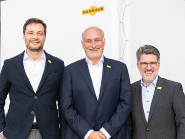 Drei Männer stehen vor einem Anhänger mit weißer Plane | © Humbaur GmbH