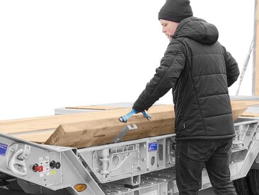 Mann sichert Holzbretter in einem Anhänger | © Humbaur GmbH 