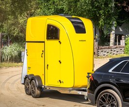 Schwarzes Auto zieht gelben Humbaur Pferdeanhänger Pegasus Style | © Humbaur GmbH