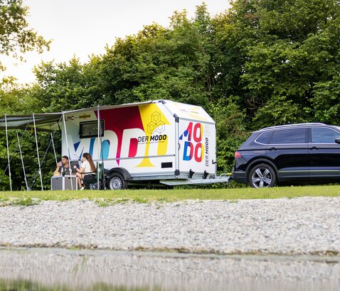 Campinganhänger MODO mit Campingzubehör steht auf Wiese am See. | © Humbaur GmbH
