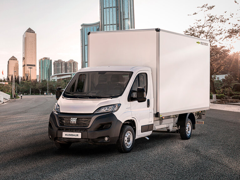 Fahrzeug mit Humbaur Flexbox-Aufbau steht aus Straße vor Hochhäusern.  | © Humbaur GmbH